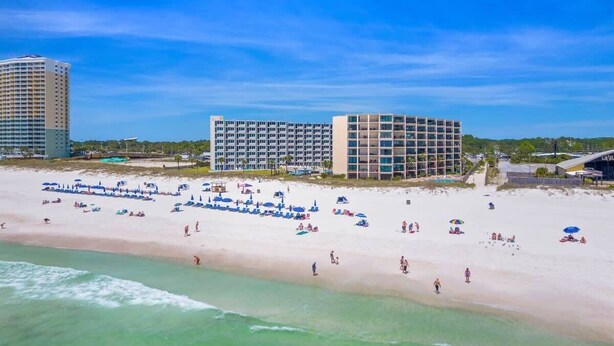A beach resort with multiple hotel buildings, a sandy beach, and umbrellas. - Moondrifter 207 - Condo with Spectacular Views (Panama City Beach)