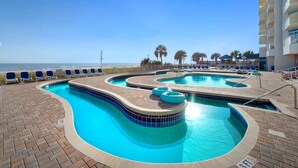 Une piscine au design incurvé, entourée de chaises longues et offrant une vue sur l’océan.