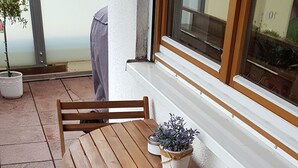 Ett träbord med stolar, en krukväxt och ett fönster med utsikt över grönområden.