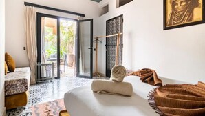 A room with a bed, a sofa, a patterned rug, and a door leading to an outdoor area. - Villa Cosy Piscine 5 Km du Centre Ville 4 Suites (Marrakech)