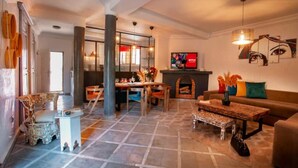 A spacious living area with a fireplace, a television, and a dining table. - Villa Cosy Piscine 5 Km du Centre Ville 4 Suites (Marrakech)