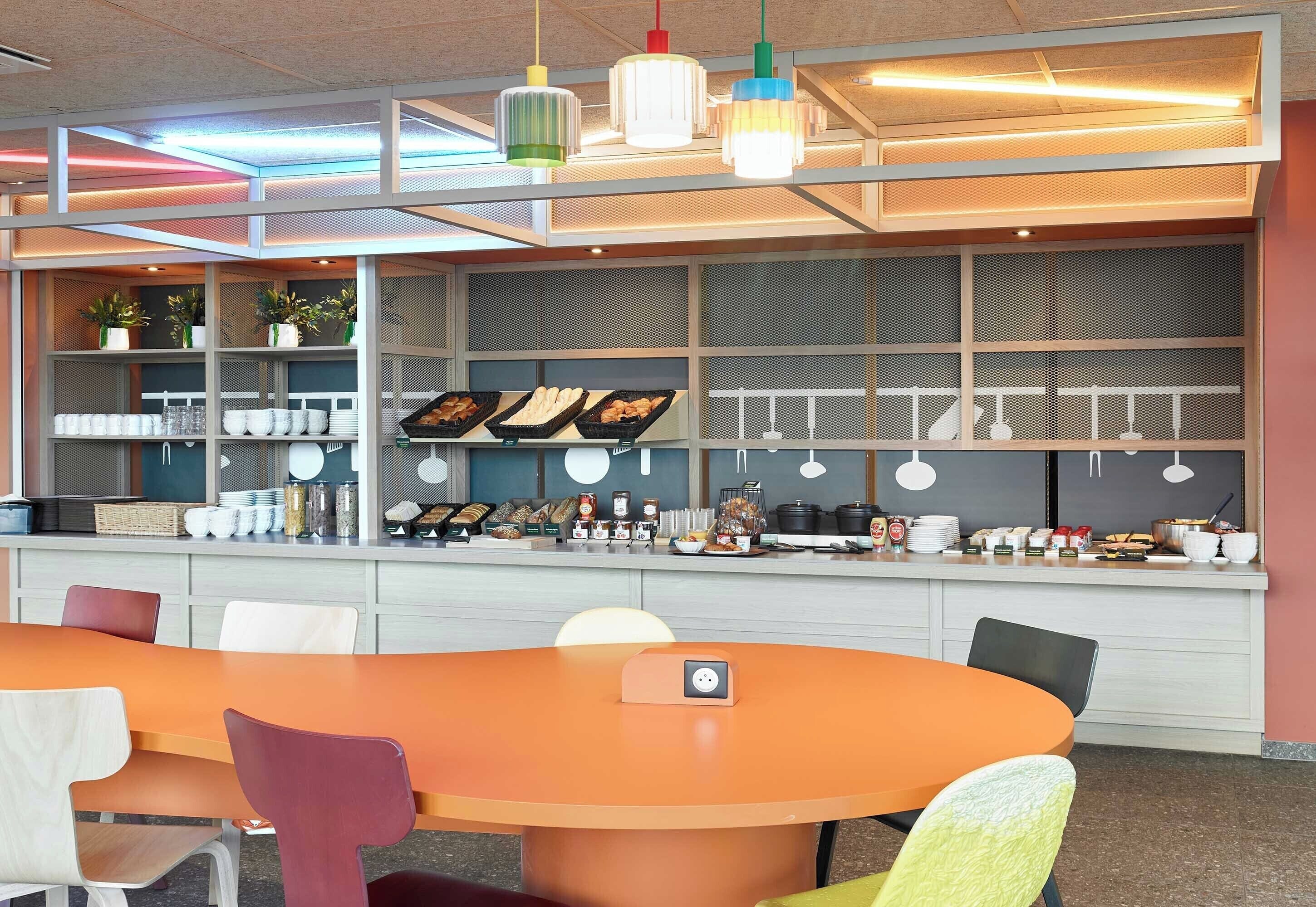 Un comedor moderno con una mesa redonda, sillas coloridas y una variedad de platos exhibidos en estanterías.