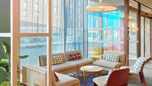 A modern lobby with seating areas, large windows, and a hanging light fixture. - B&B Hotel Marne-La-Vallée Val D'Europe (Serris)