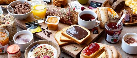 A variety of breakfast foods including pastries, fruits, and beverages on a wooden table.