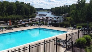 A swimming pool with lounge chairs and a view of a lake with boats.