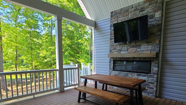 A wooden deck with a stone fireplace and a TV mounted on the wall.