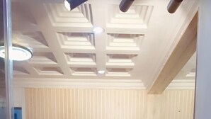 A modern reception area with a wooden reception desk, a large mirror, and a ceiling with recessed lighting. - Zek Dynasty (Lagos)