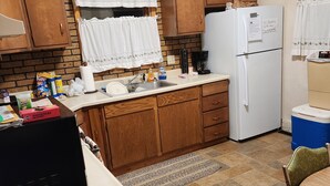 Una cucina compatta con mobili in legno, un frigorifero bianco e una macchina per il caffè.