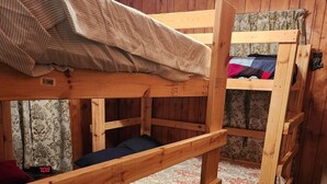 Camera con letto a castello, pareti in legno e copripiumino decorato.