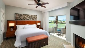 Une chambre d’hôtel avec un grand lit, un ventilateur de plafond, une cheminée et un balcon avec vue.