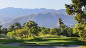 Un parcours de golf offrant une vue dégagée sur les montagnes en arrière-plan.