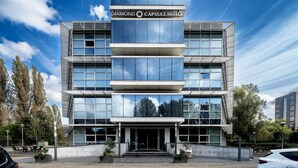 Un hôtel moderne doté d’une façade en verre, d’une enseigne bien visible indiquant « Diamond Capsule Hotel », et d’une conception symétrique comprenant plusieurs niveaux.
