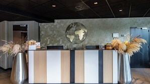 Un comptoir d’accueil orné d’une fresque représentant un globe terrestre, deux grands vases contenant de la graminée des pampas et un aménagement intérieur moderne.