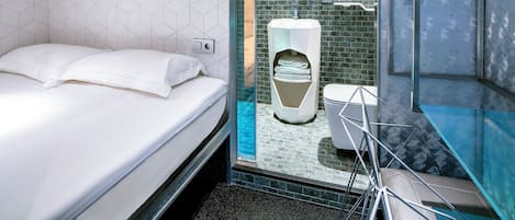 A modern hotel room with a bed, a glass shower enclosure, and a toilet.