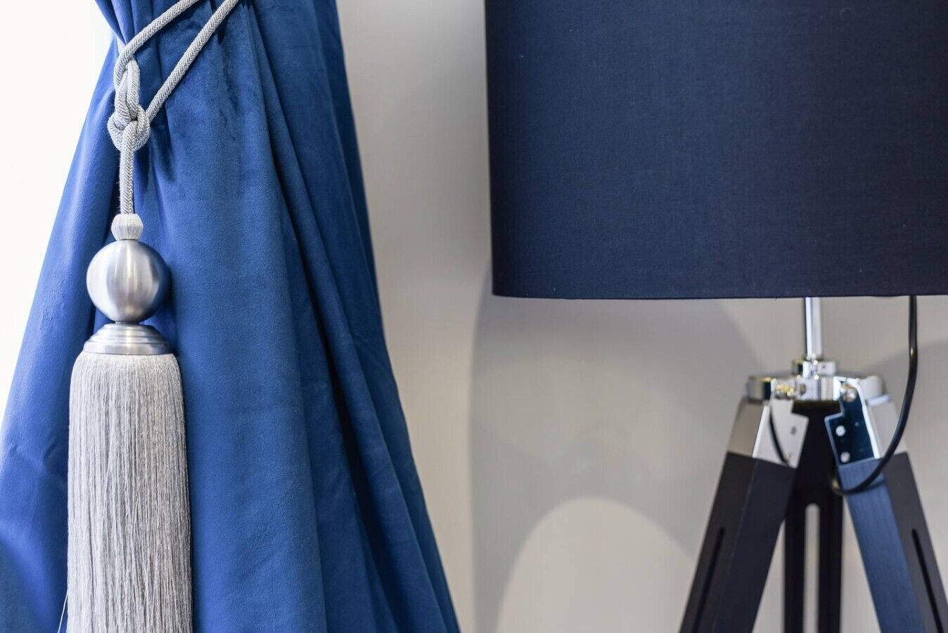 Una stanza con una tenda blu e una lampada su un treppiede.