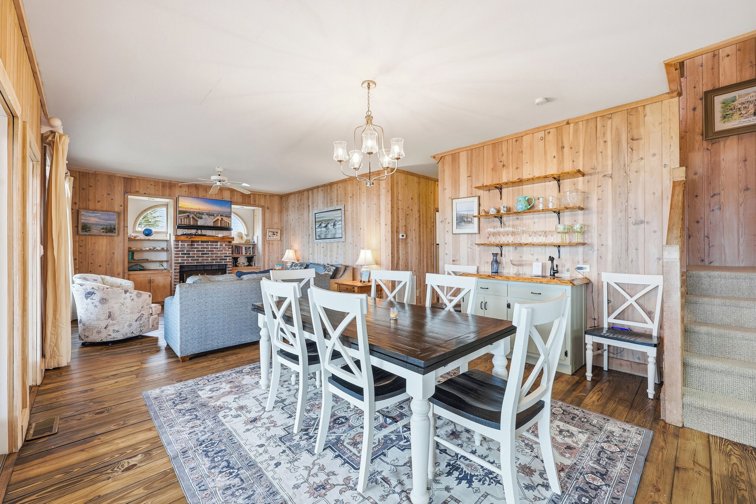 A cozy room with a wooden dining table, white chairs, a blue sofa, and a patterned rug.