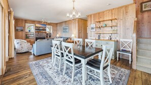 A cozy room with a wooden dining table, white chairs, a blue sofa, and a patterned rug. - Arrogantly Shabby - Oceanfront (Pawleys Island)