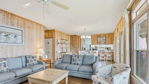 A cozy living room with a sofa, armchair, and coffee table. A kitchen is visible in the background. - Arrogantly Shabby - Oceanfront (Pawleys Island)