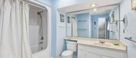 A bathroom with a bathtub, toilet, and vanity.
