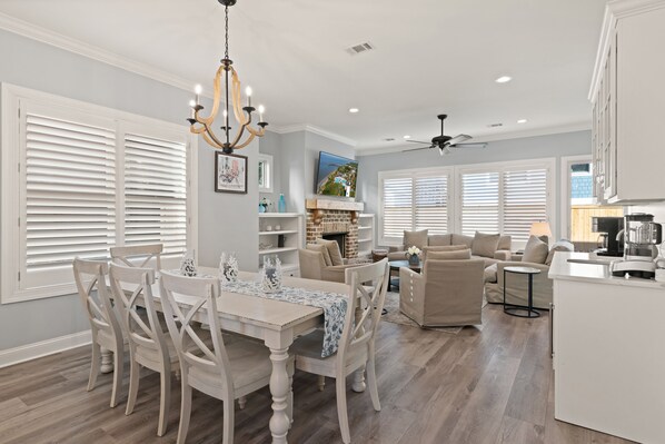 A spacious living area with a dining table, chairs, a sofa, and a kitchen area with a countertop and appliances.