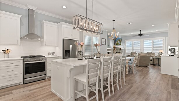 A modern kitchen with white cabinetry, a central island with bar stools, stainless steel appliances, and pendant lighting. - New Home in King City, Sleeps 10, Pool and Screened in Porch with TV! (St Simons Island)