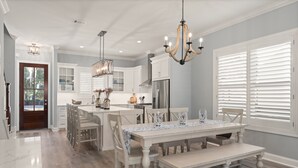 A spacious kitchen with white cabinetry, a central island, and a dining area with a bench. - New Home in King City, Sleeps 10, Pool and Screened in Porch with TV! (St Simons Island)