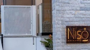 A hotel entrance with a stone facade, a metal gate, and a neon sign reading "NISO". - Niso Skiathos (Skiathos)