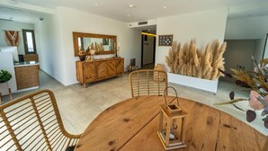 A modern dining area with a wooden table and chairs, a wooden cabinet with a mirror, and a decorative plant arrangement. - Niso Skiathos (Skiathos)