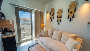 A modern living room with a sofa, a wooden coffee table, and a balcony with a view. - Niso Skiathos (Skiathos)