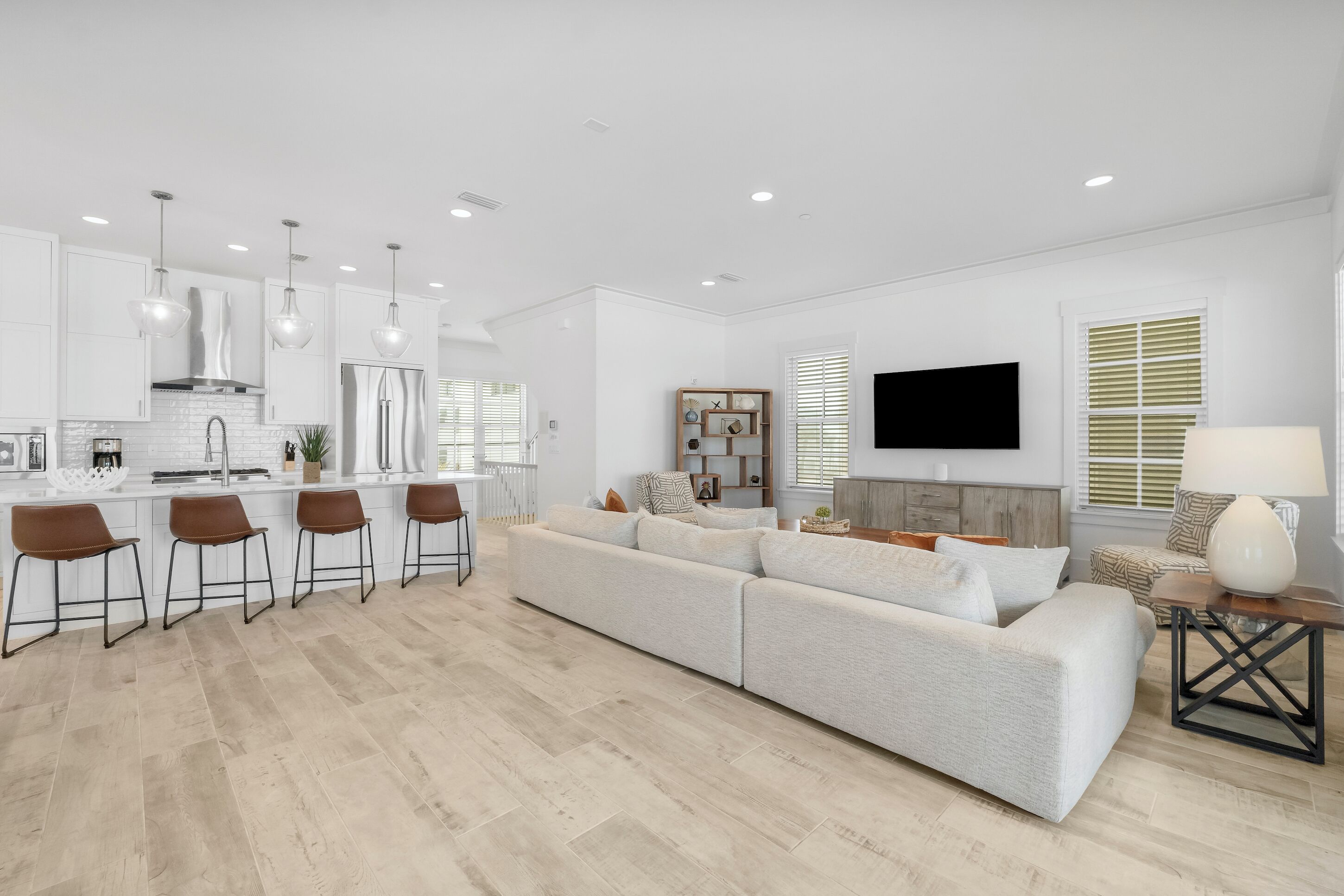 A modern kitchen with white cabinets, a stainless steel refrigerator, and pendant lighting.