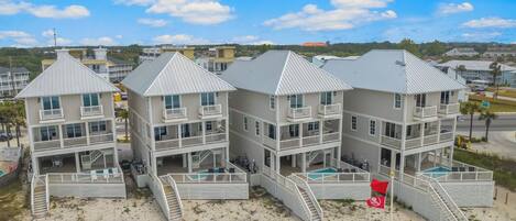 Propiedad frente al mar con varias edificaciones, cada una con balcones y piscina.