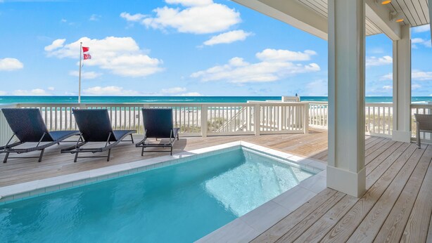 A pool area with lounge chairs and a view of the ocean. - Beach House - Reel Em Inn by PHG (Panama City Beach)
