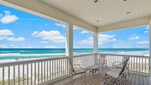 A covered wooden deck with white railings overlooking a beach. - Beach House - Reel Em Inn by PHG (Panama City Beach)