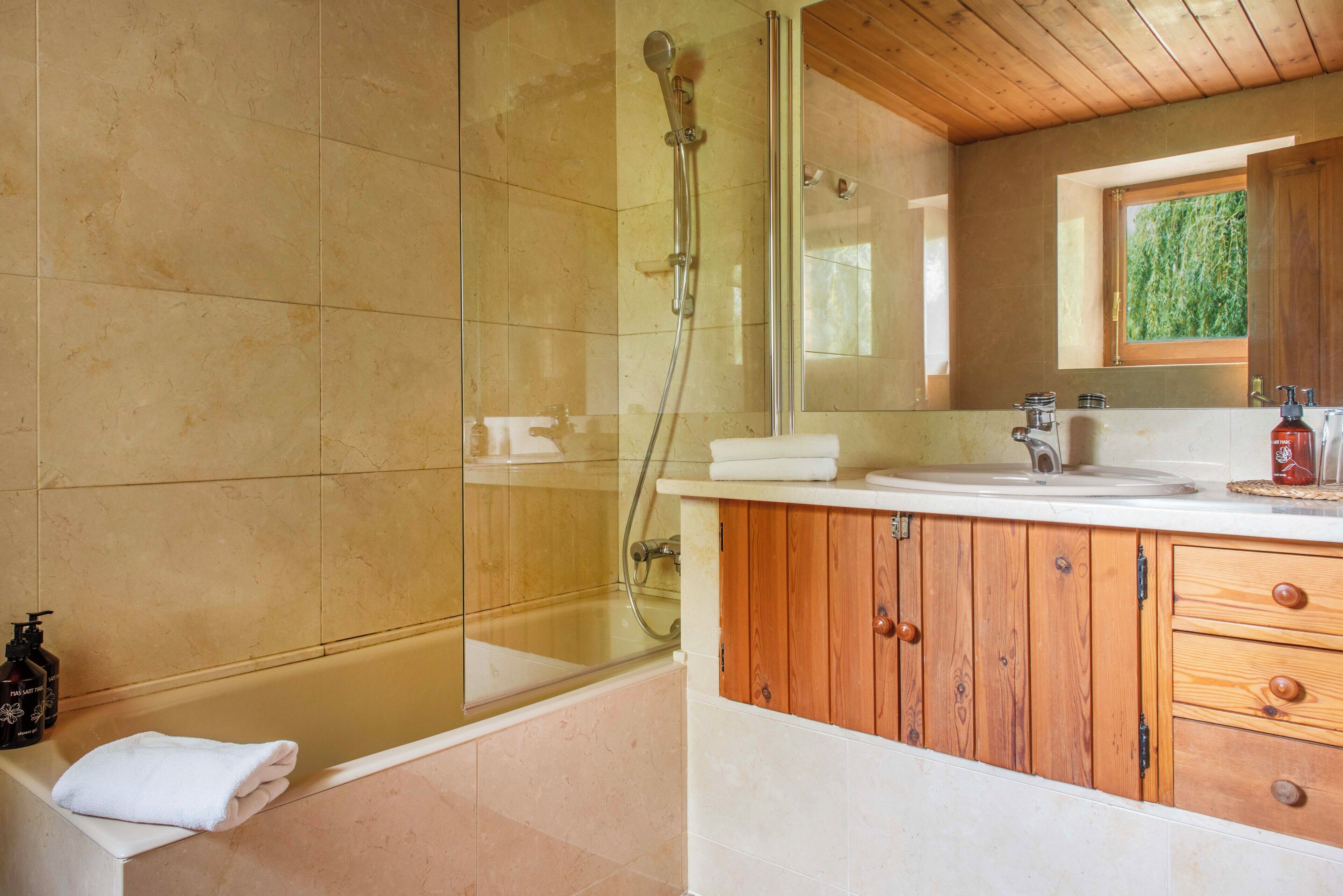 Un baño con ducha de vidrio, bañera y tocador de madera con espejo.