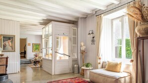 A cozy living room with a sofa, a red patterned rug, and a large window with curtains. - Mas Sant Marc (Puigcerda)