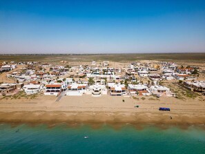 An aerial view of a coastal town with numerous white buildings, a sandy beach, and clear turquoise waters. - Casa del Mar Azul – Near Beach, Las Conchas (Puerto Penasco)