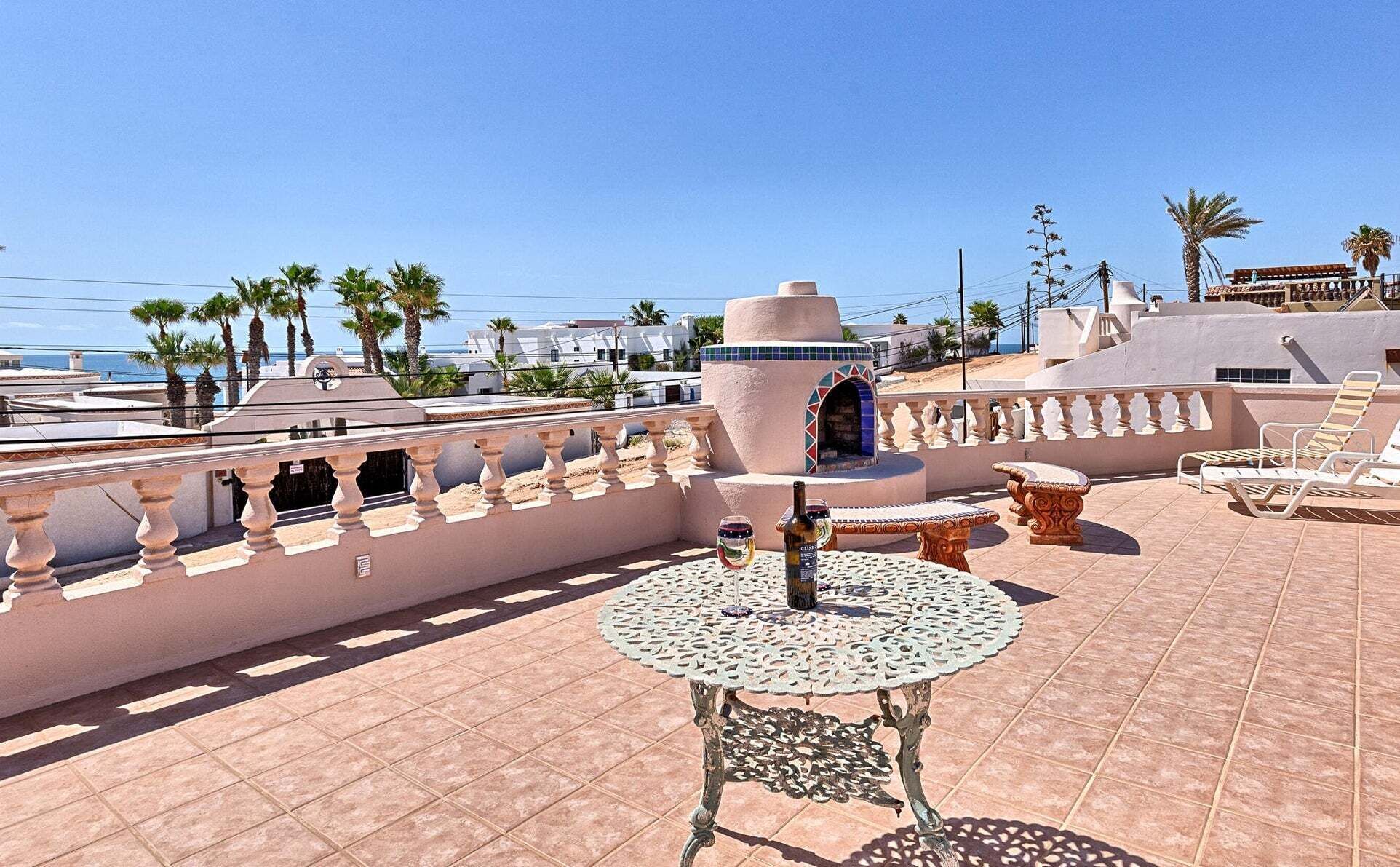A rooftop terrace with a round table, lounge chairs, and a decorative wall.