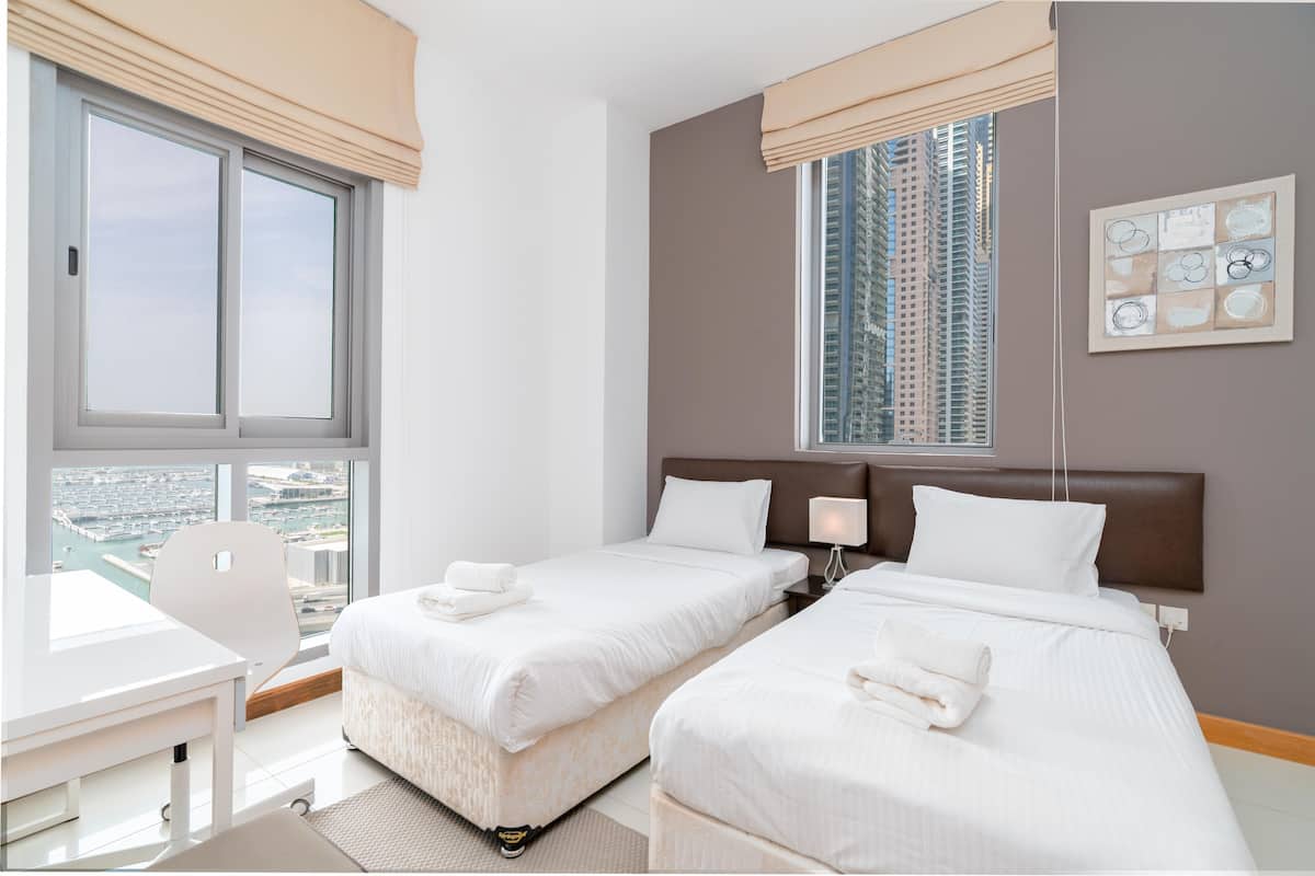 A hotel room with two beds, a desk, and a chair.