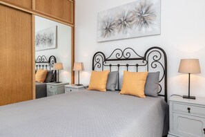 A neatly arranged bedroom with a bed, two bedside tables, and a nightstand. - Lota Beach House by AlgarveManta (10T2) (Manta Rota)