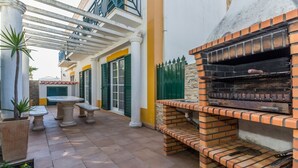 Un patio con horno de ladrillo, mobiliario exterior y una pérgola.