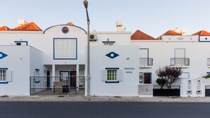 Un edificio bianco con dettagli blu, un ingresso centrale con una porta e finestre, e un piccolo balcone.