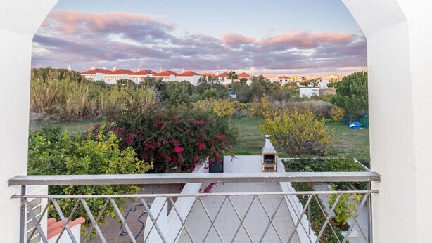 Un balcone con vista su una zona residenziale, con case e vegetazione.