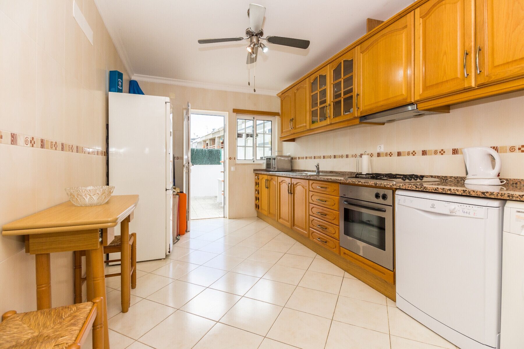 Una cocina con armarios de madera, un refrigerador blanco, una estufa y un lavavajillas.