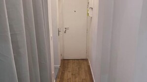 A narrow hallway with wooden flooring, white walls, and a door at the end. - T2 Cozy à 20min du Stade de France (Saint-Denis)