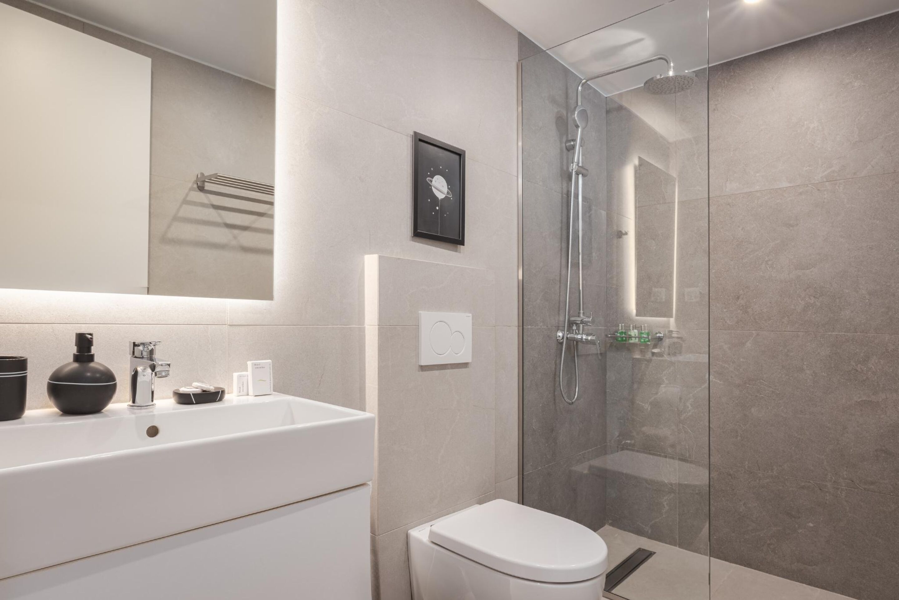 A modern bathroom with a large white sink, a toilet, and a glass-enclosed shower.
