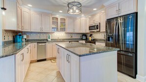 A spacious kitchen with light-colored cabinets, granite countertops, stainless steel appliances, and a central island. - 🌴3 Palms- 3BD Handicap Accessible Home w/ Pool!🌴 (Carolina Beach)