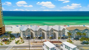 Un hotel frente a la playa con varias construcciones, una playa de arena y el océano al fondo.