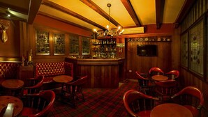 A bar area with wooden walls, a red plaid carpet, and a variety of seating options including booths and tables. - Hotel Chicala S.A.S (Neiva)