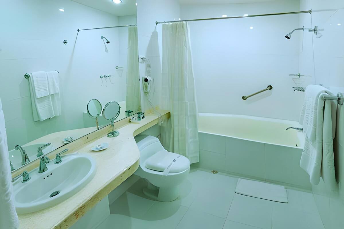 A modern bathroom with a sink, two mirrors, a toilet, and a bathtub.