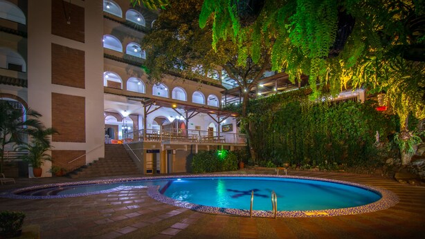 A hotel with a swimming pool, multiple floors with balconies, and lush greenery. - Hotel Chicala S.A.S (Neiva)